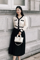 a lady in a white cardigan with black trim and a black long skirt